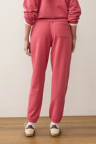 Person wearing pink sweatpants and a matching top on a plain background