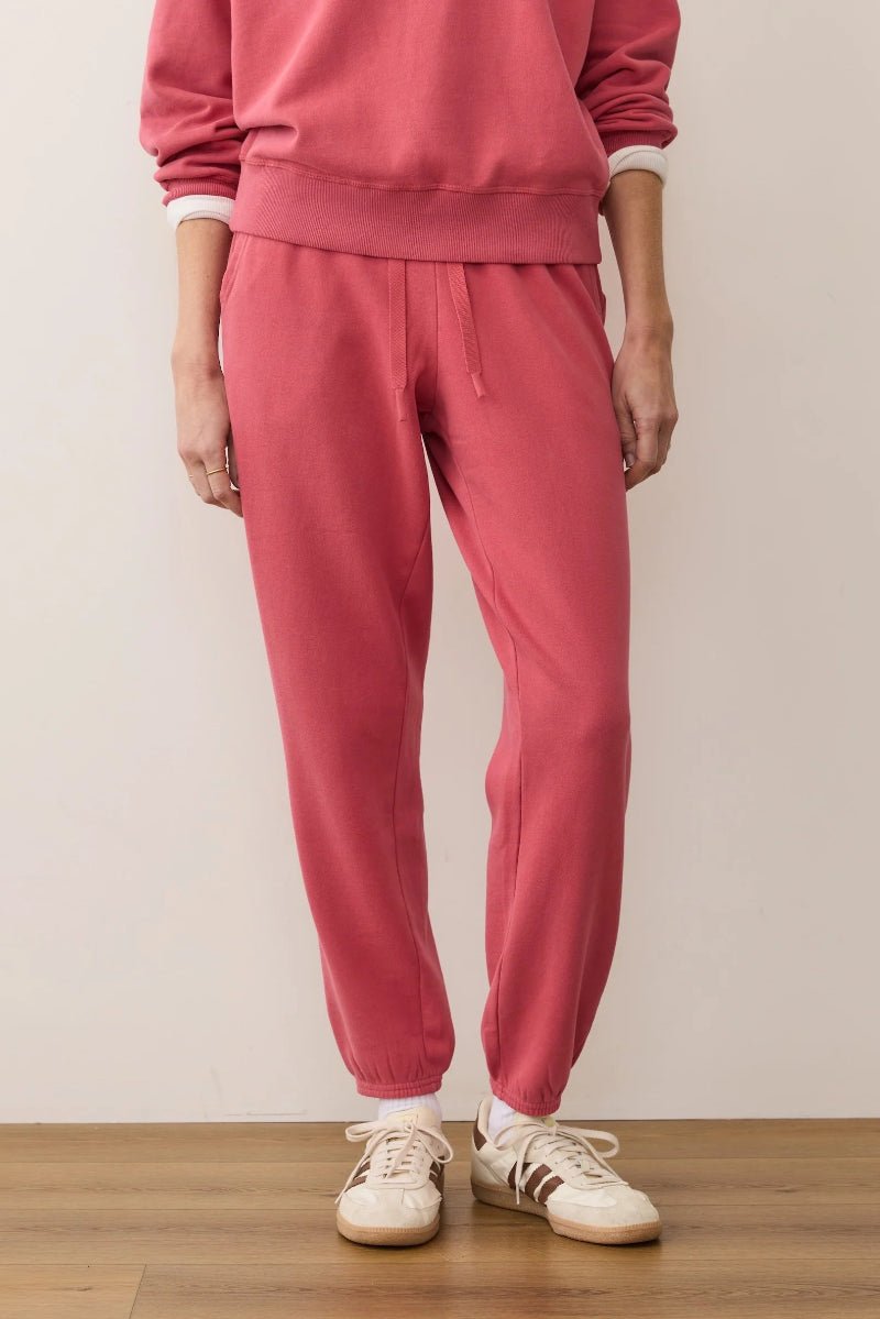 Person wearing a pink tracksuit with white sneakers on a plain background