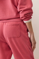 Person wearing a pink tracksuit with a neutral background