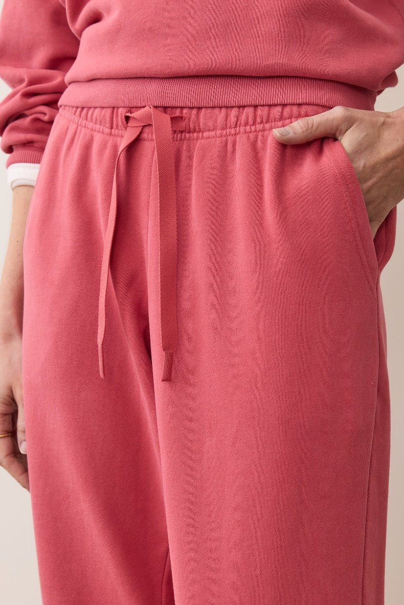Person wearing pink sweatpants with a neutral background