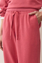Person wearing pink sweatpants with a neutral background