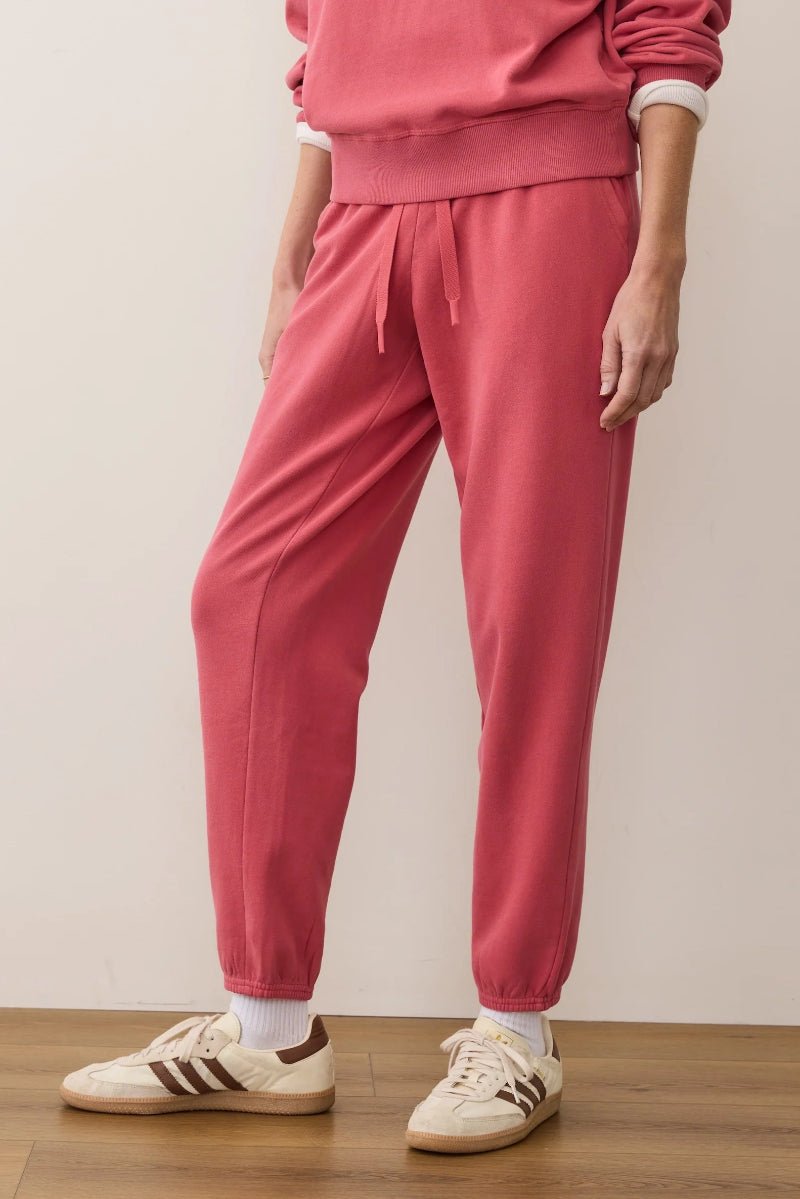 Person wearing a pink tracksuit with white sneakers on a plain background