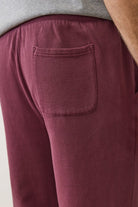 Maroon sweatpants with a pocket on a plain background