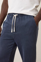 Navy blue pants with a white drawstring on a neutral background