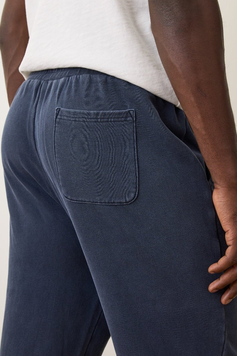 Navy blue pants with a pocket on a neutral background