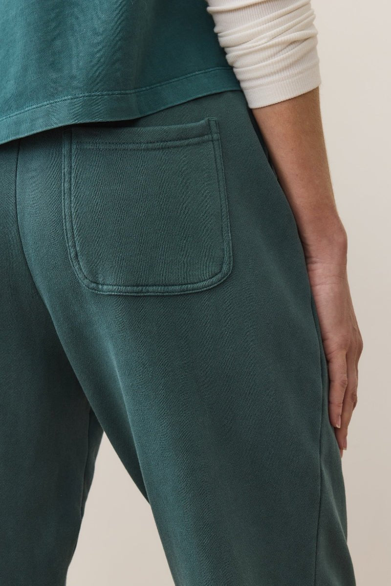 Teal pants with a pocket on a neutral background