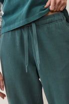 Teal jogger pants with a tie detail worn by a person on a neutral background