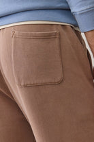 Close-up of brown pants with a pocket, wearing a blue sweater.