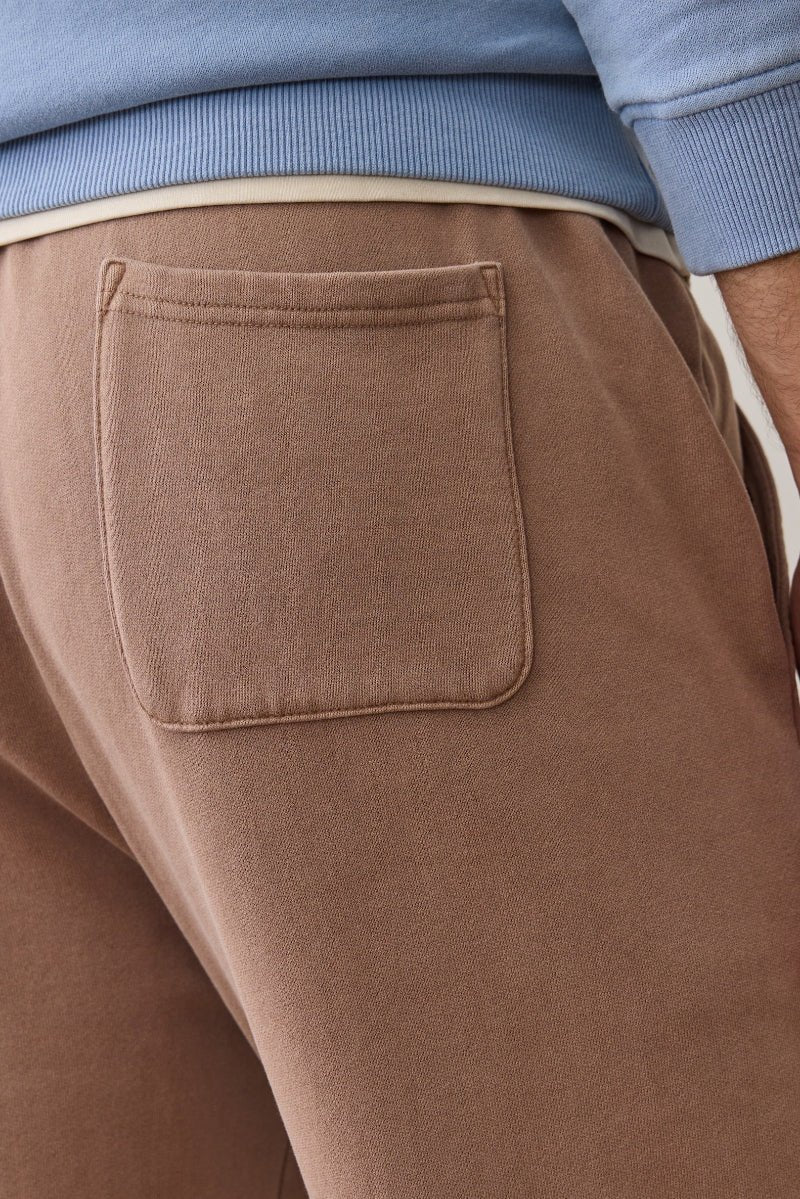 Close-up of brown pants with a pocket, wearing a blue sweater.