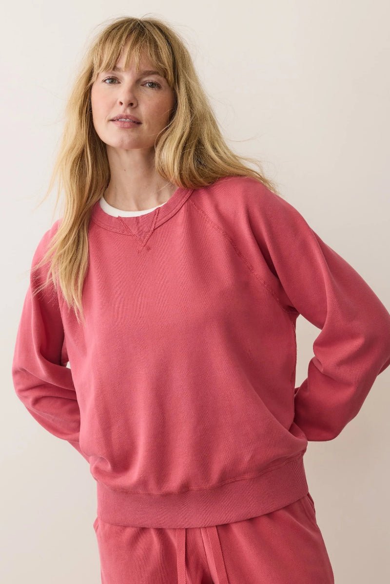 Person wearing a pink sweatshirt and pants against a plain background