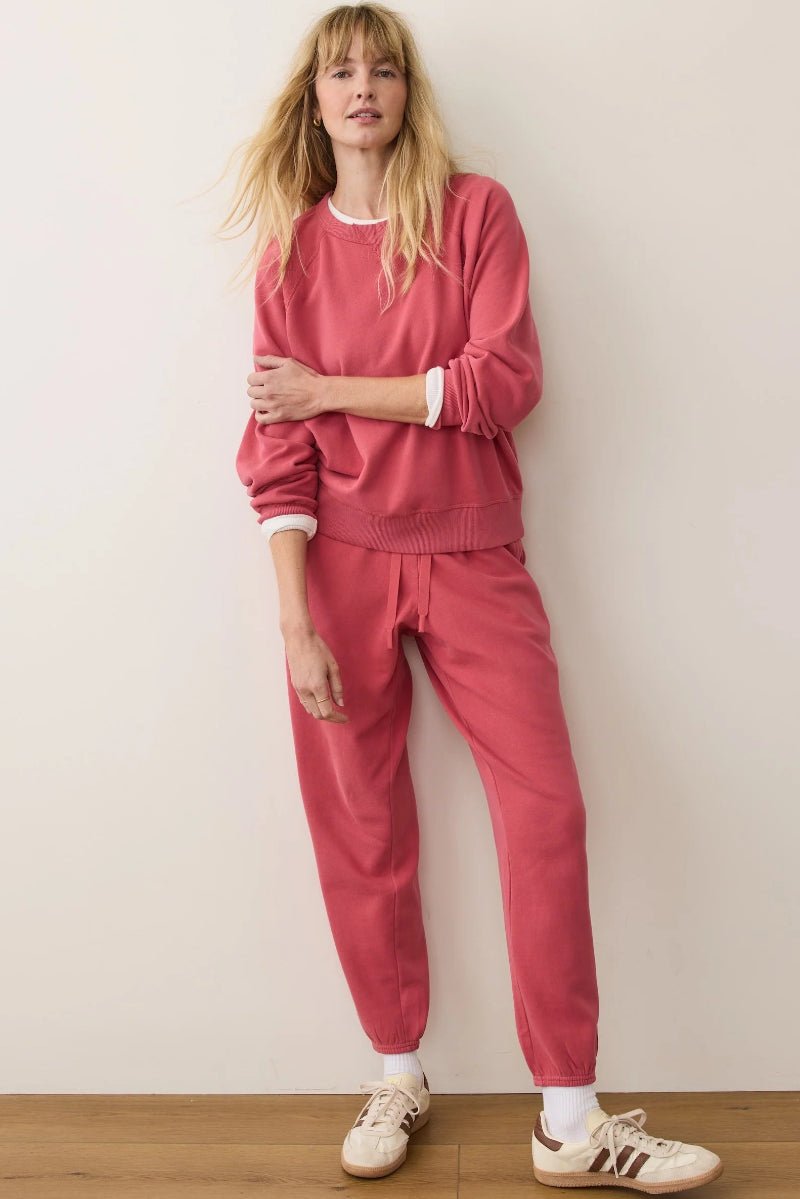 Person wearing a pink outfit with white sneakers against a plain background