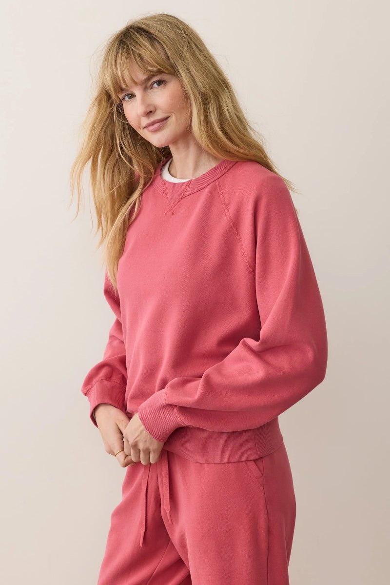 Woman wearing a pink sweatshirt and pants against a plain background