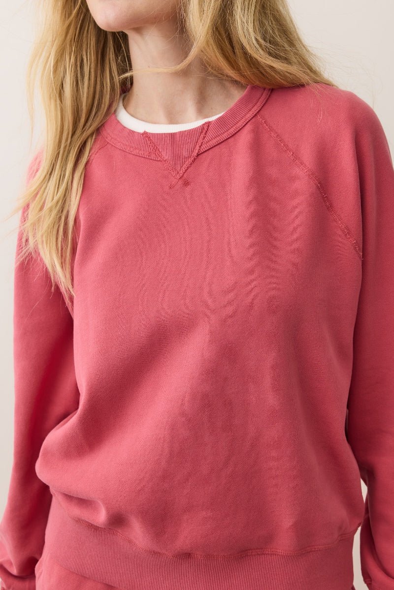 Person wearing a red sweatshirt against a plain background