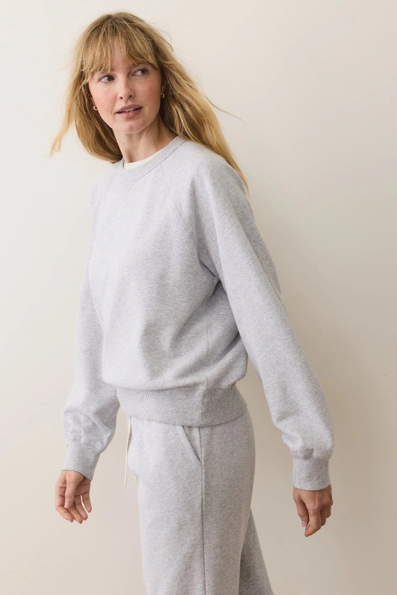 Woman wearing a gray sweatshirt and pants against a plain background