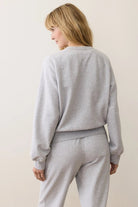 Person wearing a gray sweatshirt and pants on a plain background