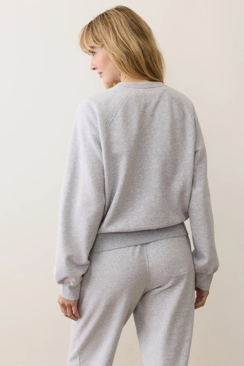 Person wearing a gray sweatshirt and pants on a plain background