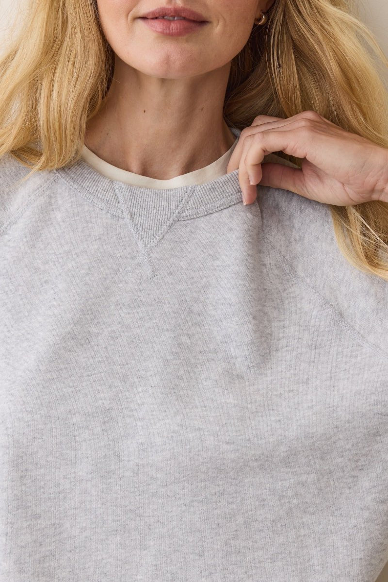 Person wearing a gray sweatshirt with a neutral background