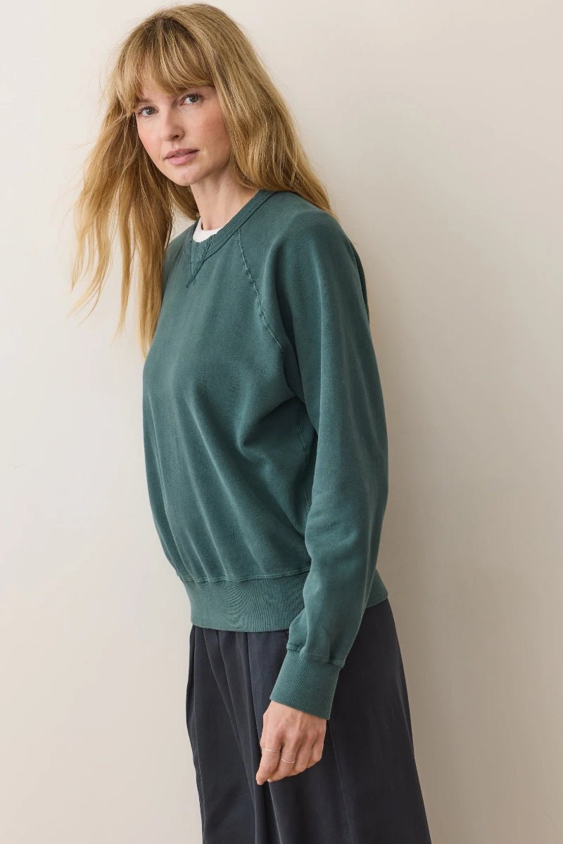Woman wearing a green sweater against a plain background