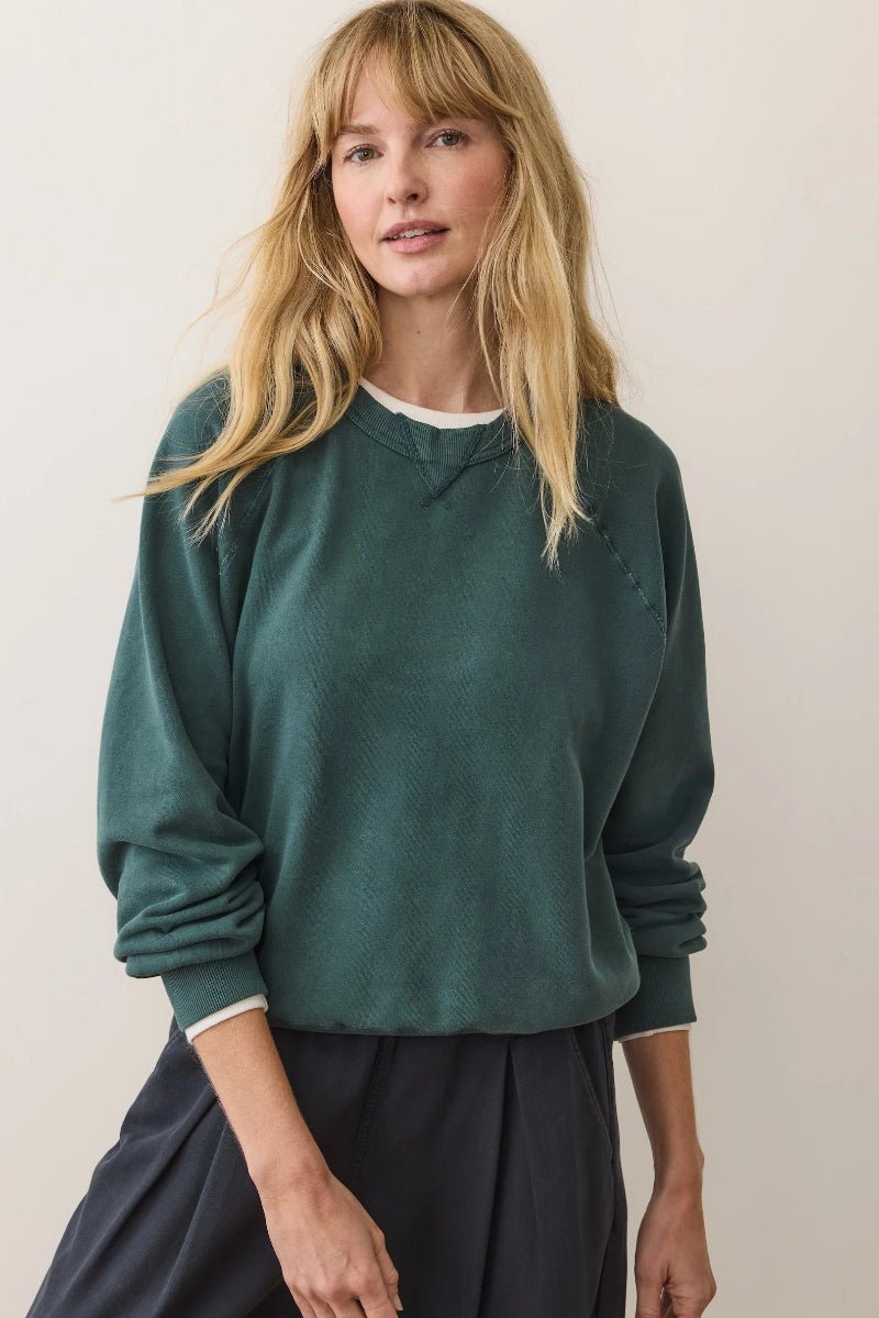Woman wearing a green sweater against a plain background