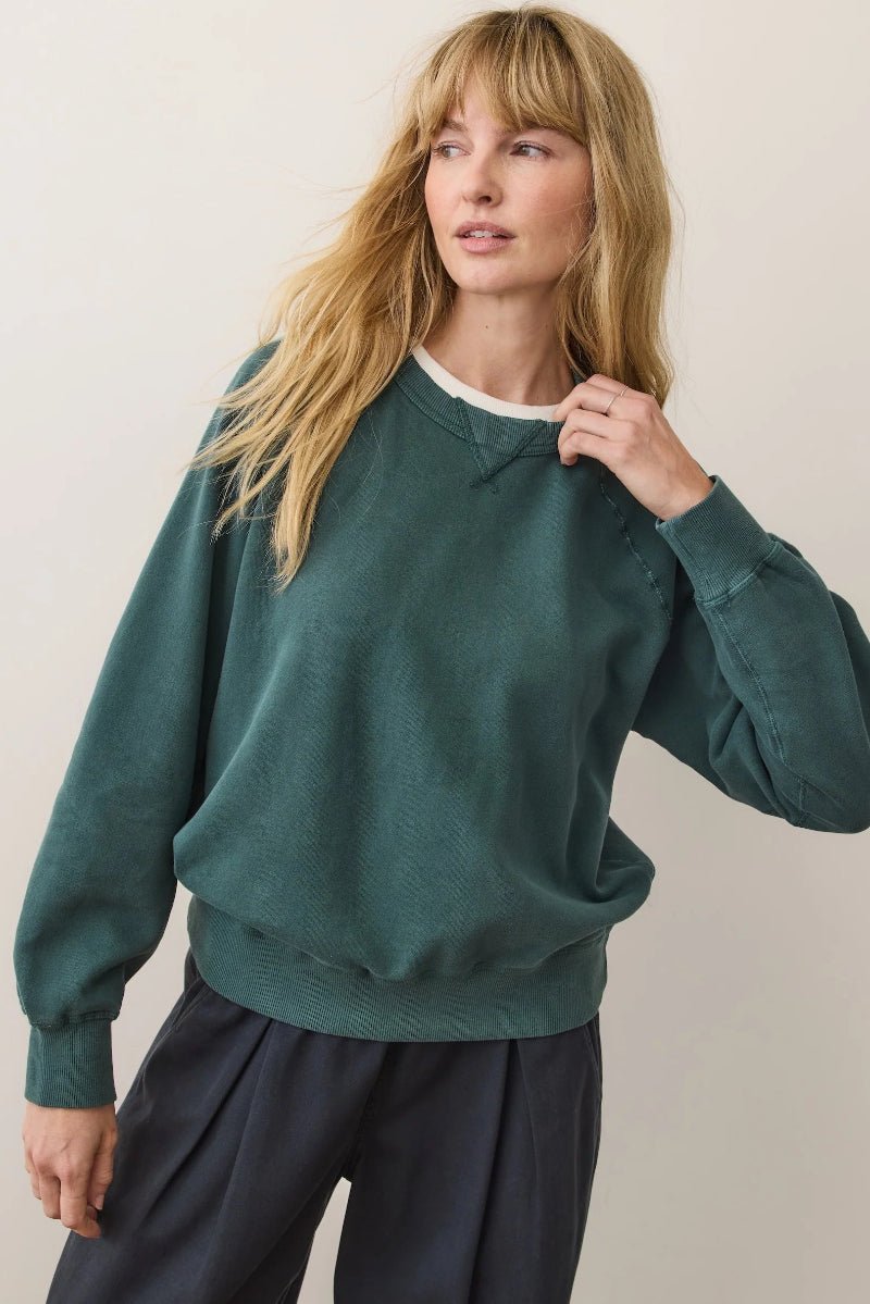 Woman wearing a green sweater against a plain background