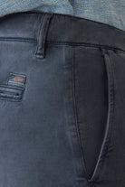 Close-up of dark gray pants with a brand logo on the pocket, worn by a person.