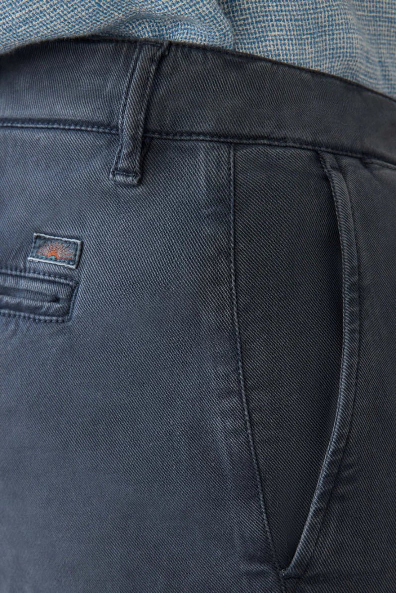 Close-up of dark gray pants with a brand logo on the pocket, worn by a person.