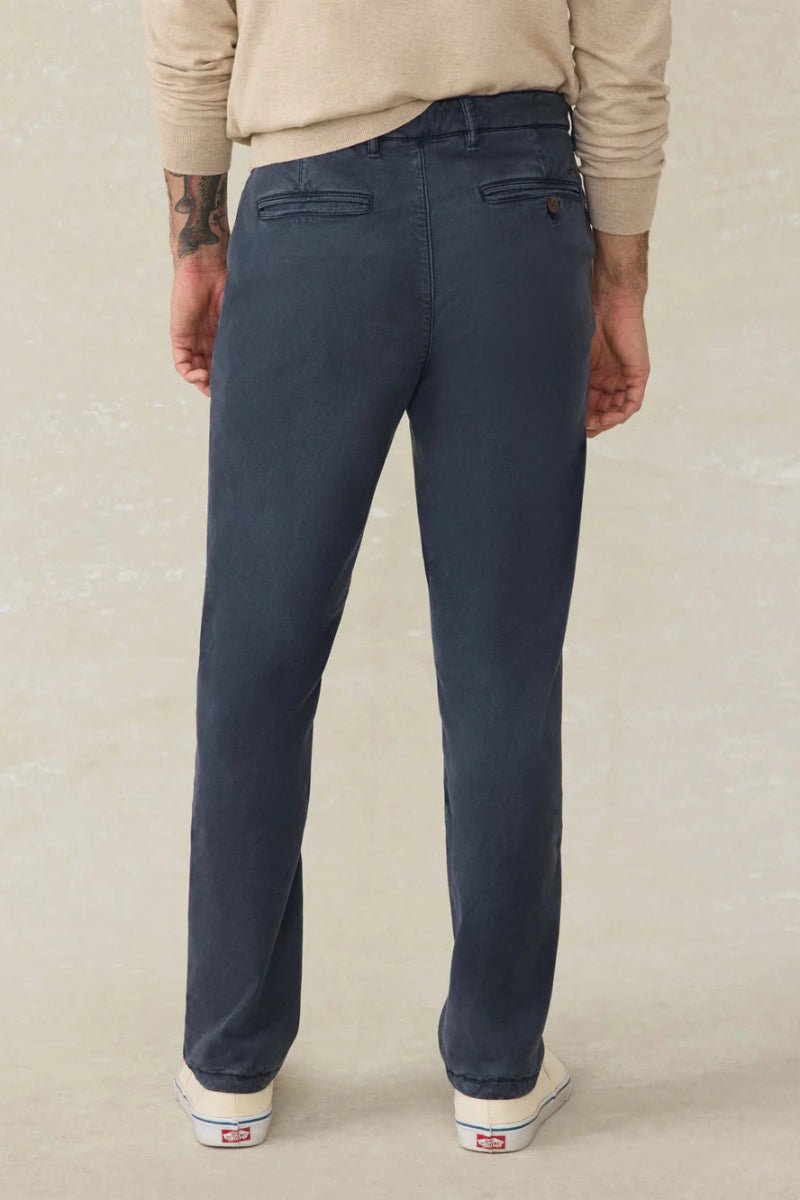 Person wearing navy blue pants on a beige background