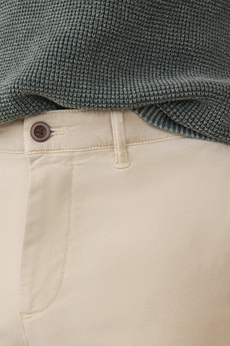 Close-up of beige pants with a green textured sweater on top