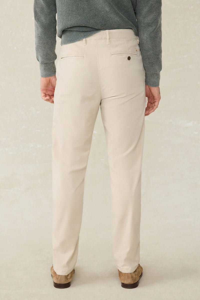 Person wearing beige pants and a green sweater on a plain background