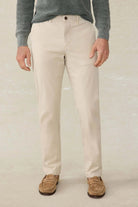 Person wearing beige pants and a gray sweater on a plain background