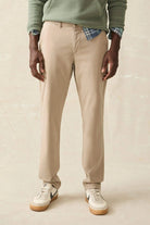 Person wearing beige pants with a plain background
