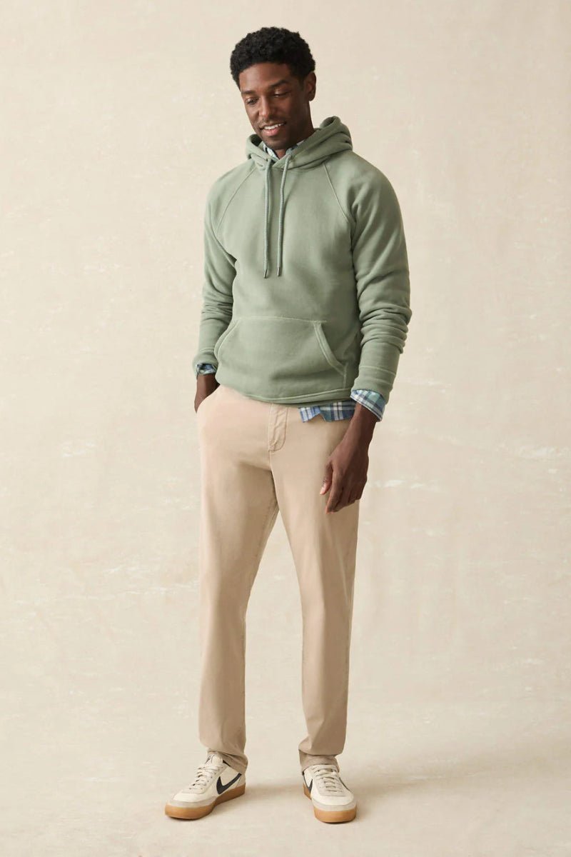 Man wearing a green hoodie and beige pants against a beige background