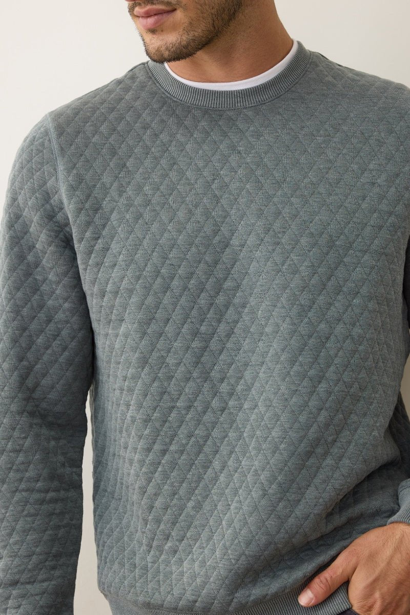 Man wearing a textured gray sweater against a plain background
