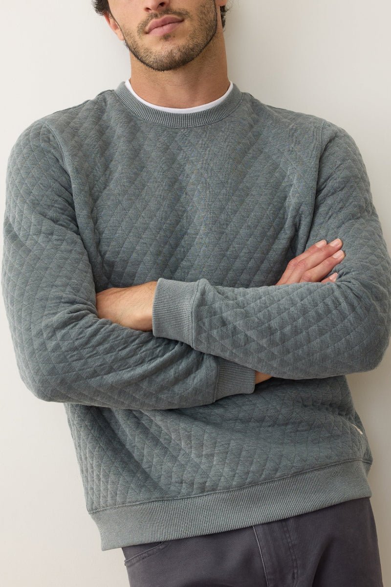 Man wearing a textured gray sweater against a plain background