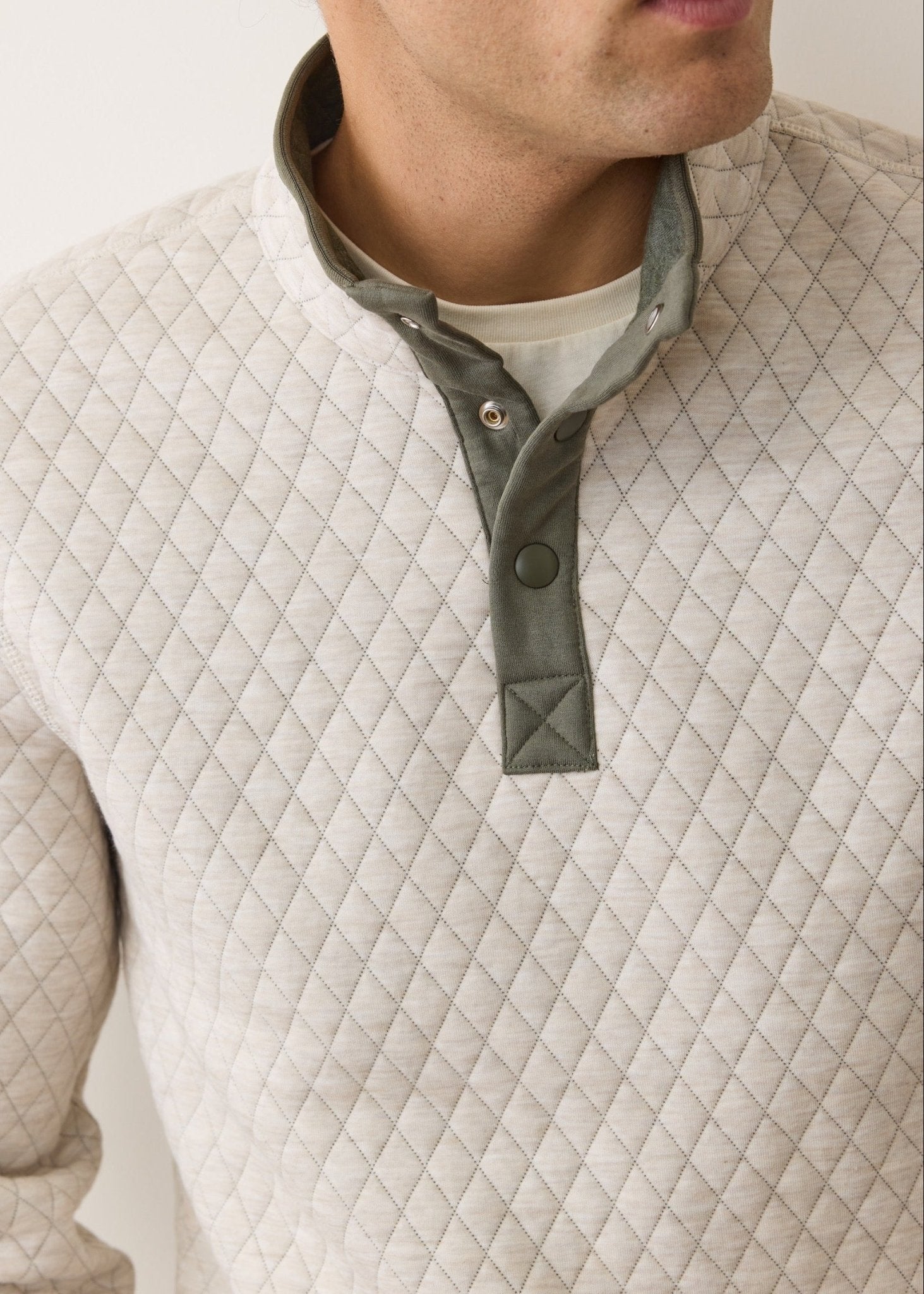Quilted beige jacket with a green collar on a neutral background