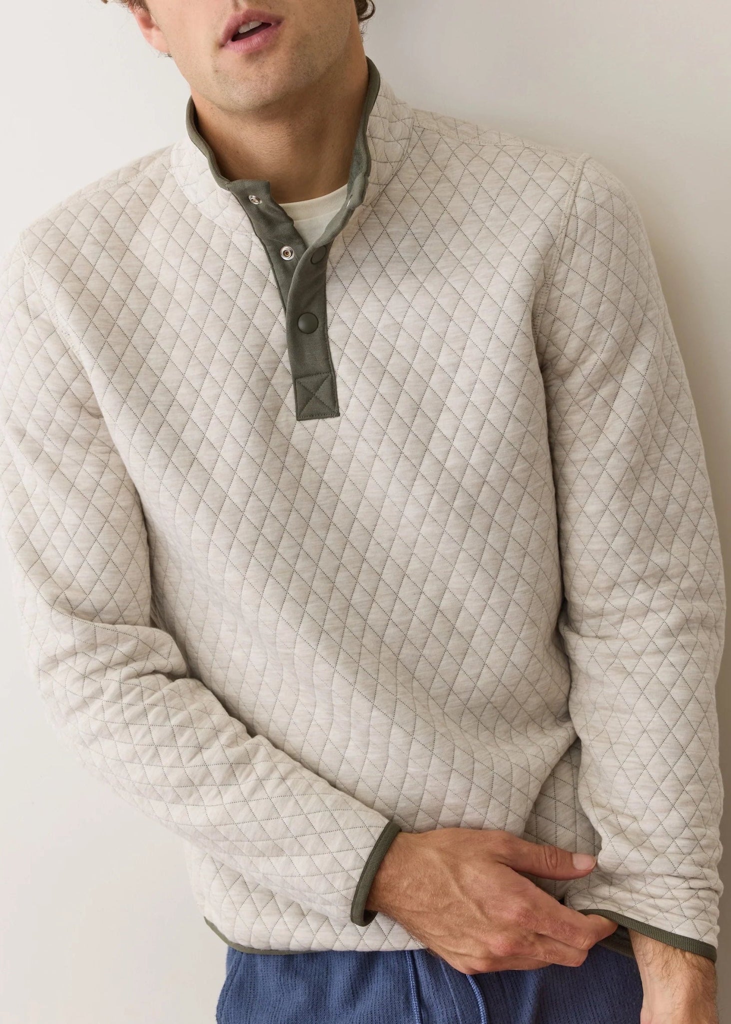 Man wearing a quilted beige pullover against a plain background