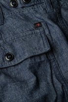 Close-up of a blue denim jacket with buttons and a brand logo.