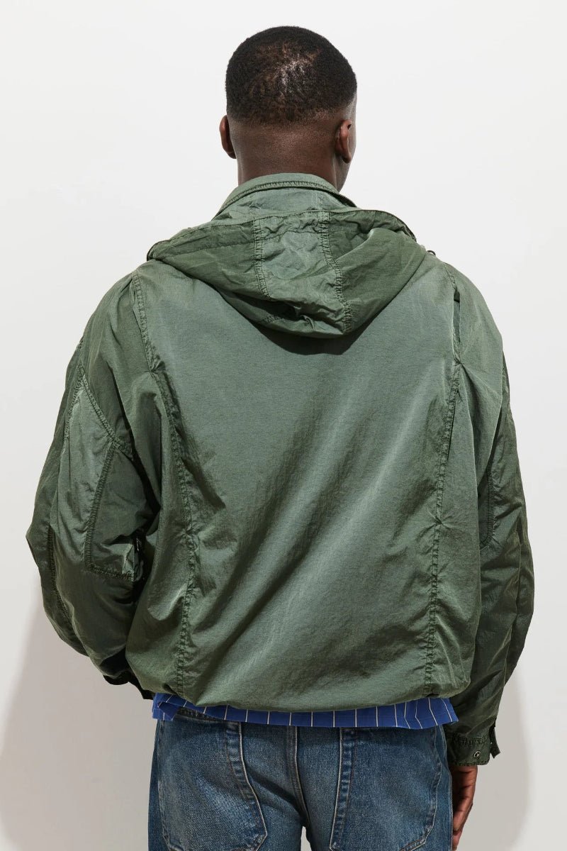 Person wearing a green jacket with a hood on a white background