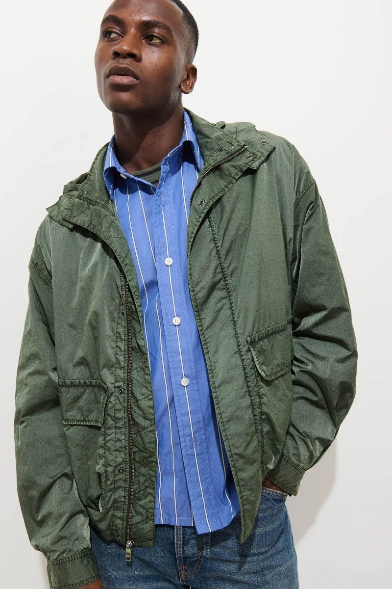 Man wearing a green jacket over a blue shirt on a white background
