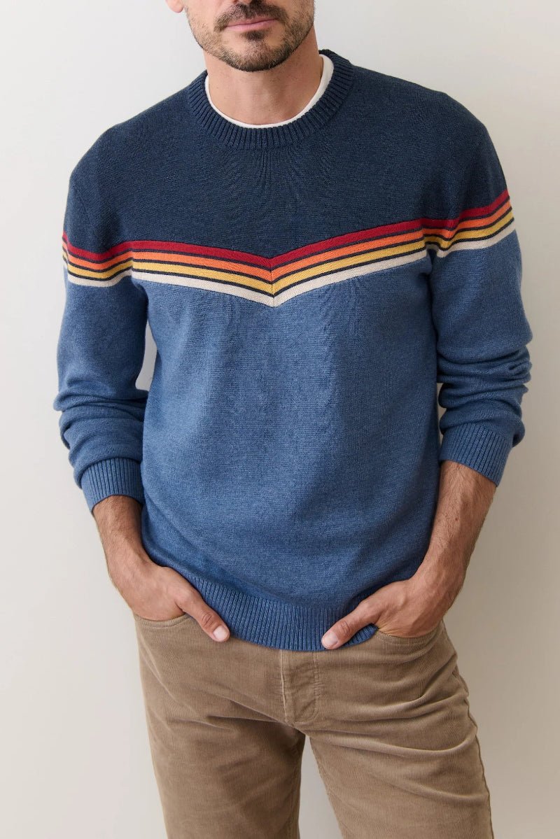 Man wearing a blue sweater with colorful stripes against a plain background