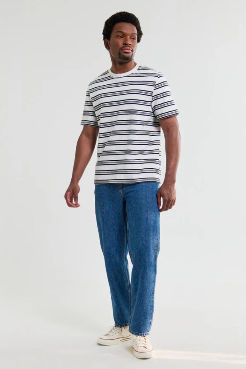 Man wearing a striped shirt and blue jeans on a white background