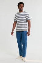 Man wearing a striped shirt and blue jeans on a white background