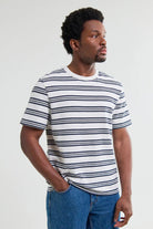 Man wearing a striped t-shirt and jeans against a plain background