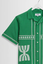 Green shirt with white patterns on a hanger against a white background