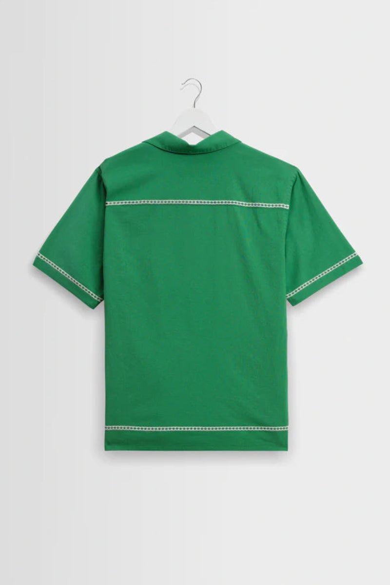 Green polo shirt on a hanger against a light gray background
