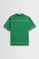 Green polo shirt on a hanger against a light gray background