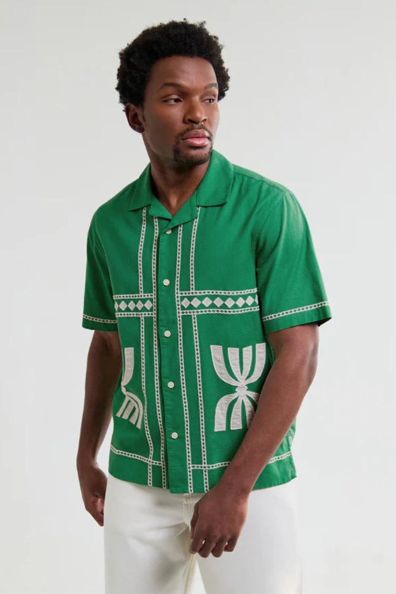 Man wearing a green patterned shirt against a white background