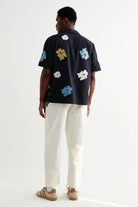 Person wearing a navy shirt with white floral patterns on a white background