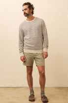 Man wearing a striped sweater and shorts standing against a plain background