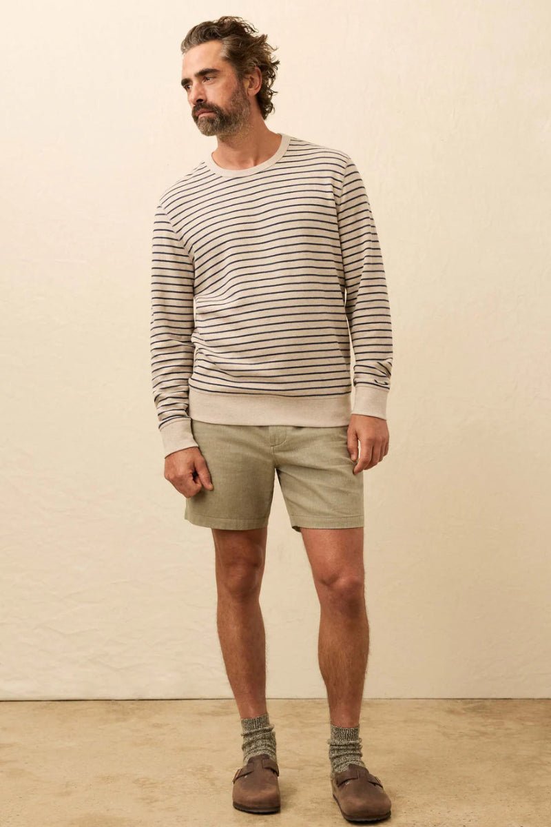 Man wearing a striped sweater and shorts standing against a plain background